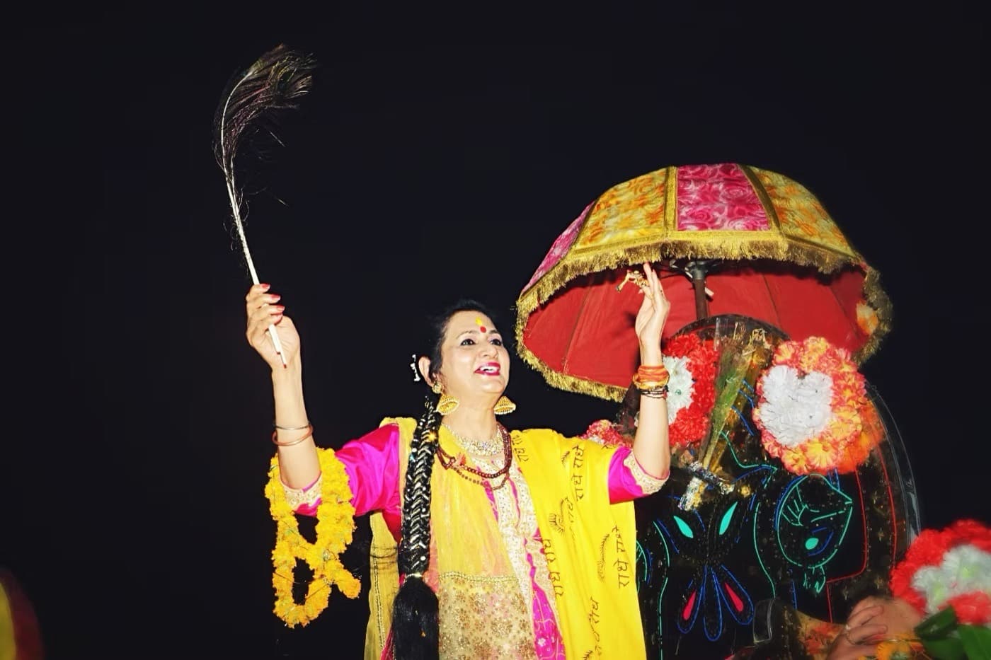 Shri Maa performing a devotional dance with a peacock feather.